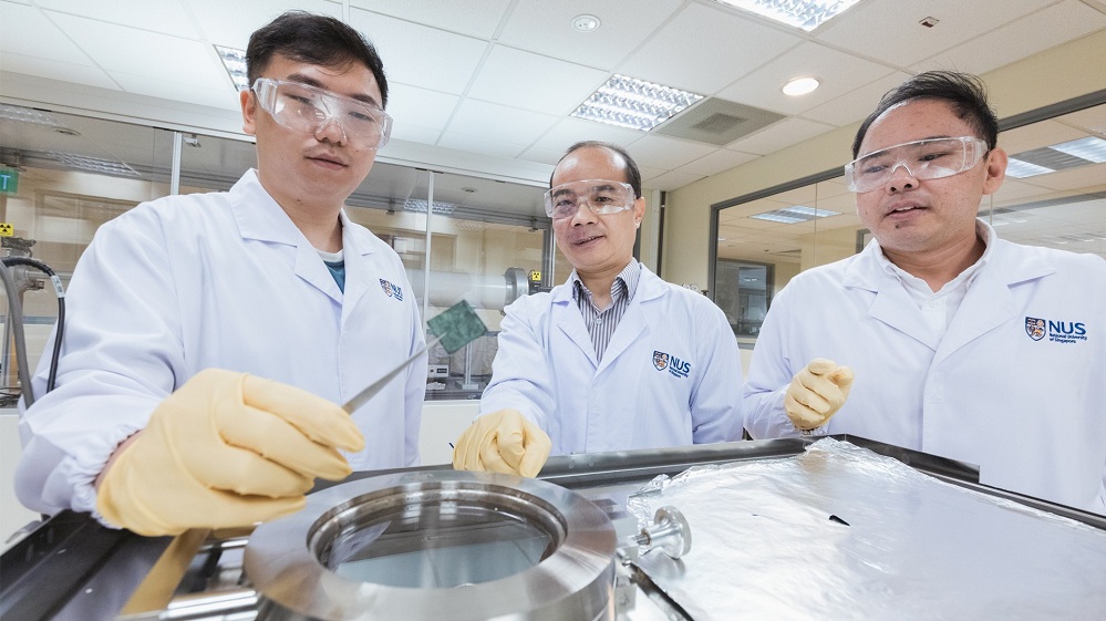 An NUS team led by Assoc Prof Xue Jun Min (centre) has found that light can trigger a new mechanism in a catalytic material used extensively in water electrolysis (held up by Mr Zhong Haoyin), where water is broken down into hydrogen and oxygen. The result is a more energy-efficient method of obtaining hydrogen. Dr Vincent Lee Wee Siang (right) is a member of the research team.